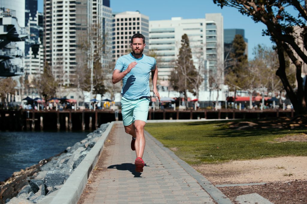 Athletic young man running in the nature. Run in city park.