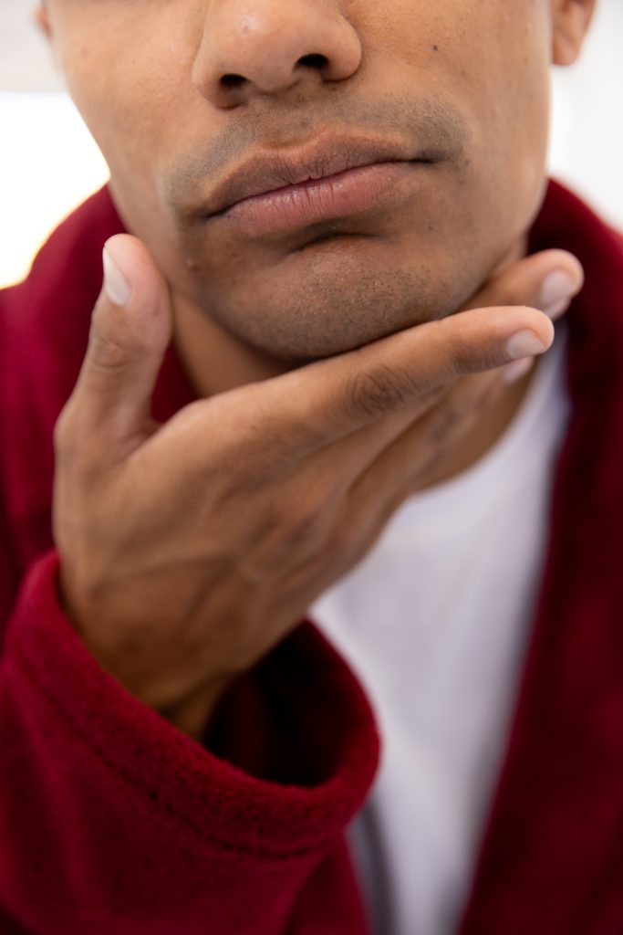 Biracial man touching his face in bathroom at home. Self care, lifestyle and domestic life, unaltered.