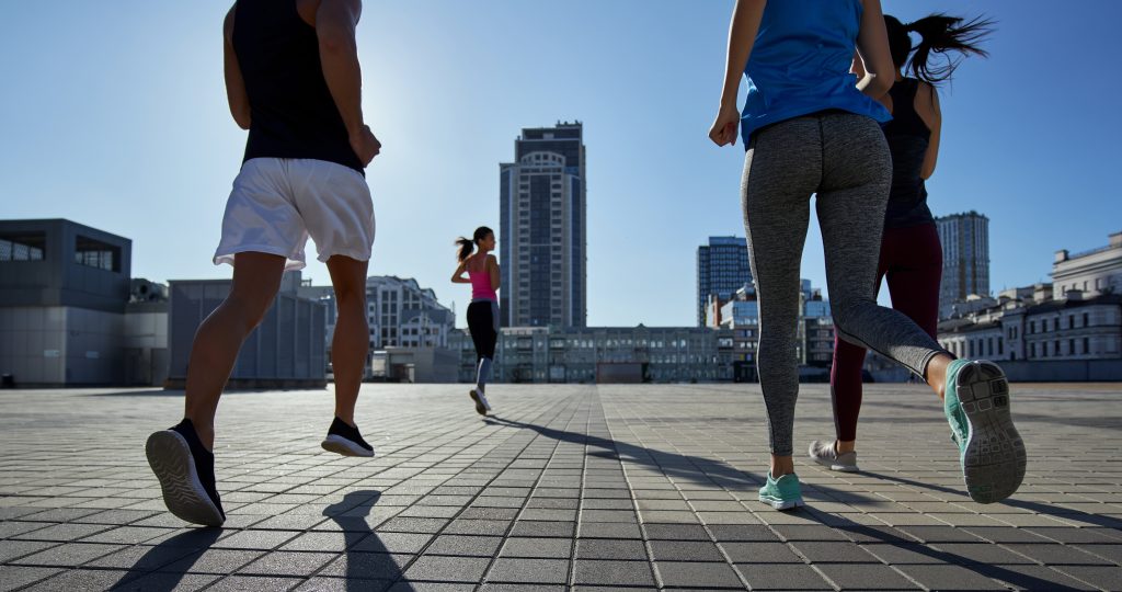 Company of young people running on cityscape background