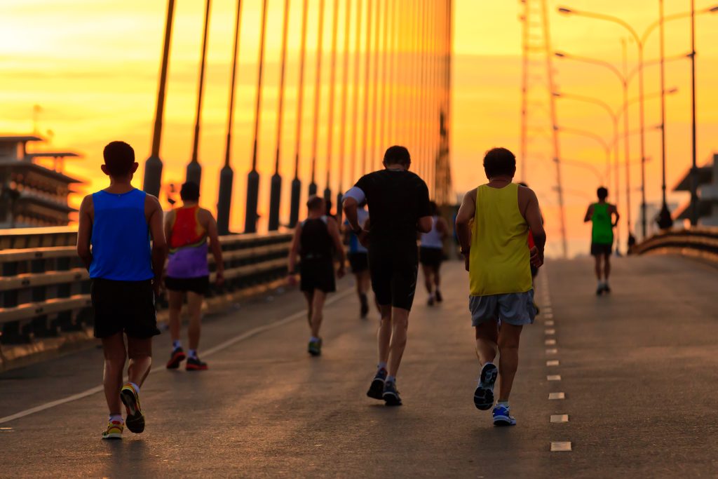 Runners run on bridge in the morning